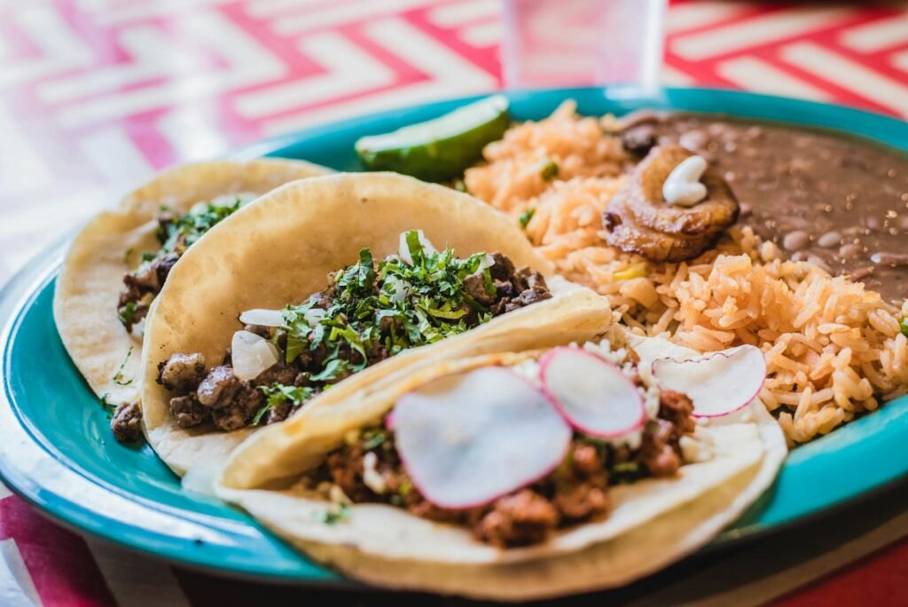A home dinner setup with rice, beans, slaw, salsa, herbs, and other toppings laid out buffet-style.