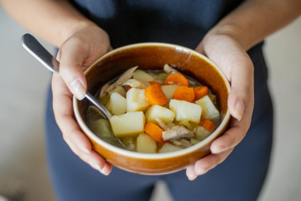 A pot of white bean and potato soup being blended until smooth on a home stove.