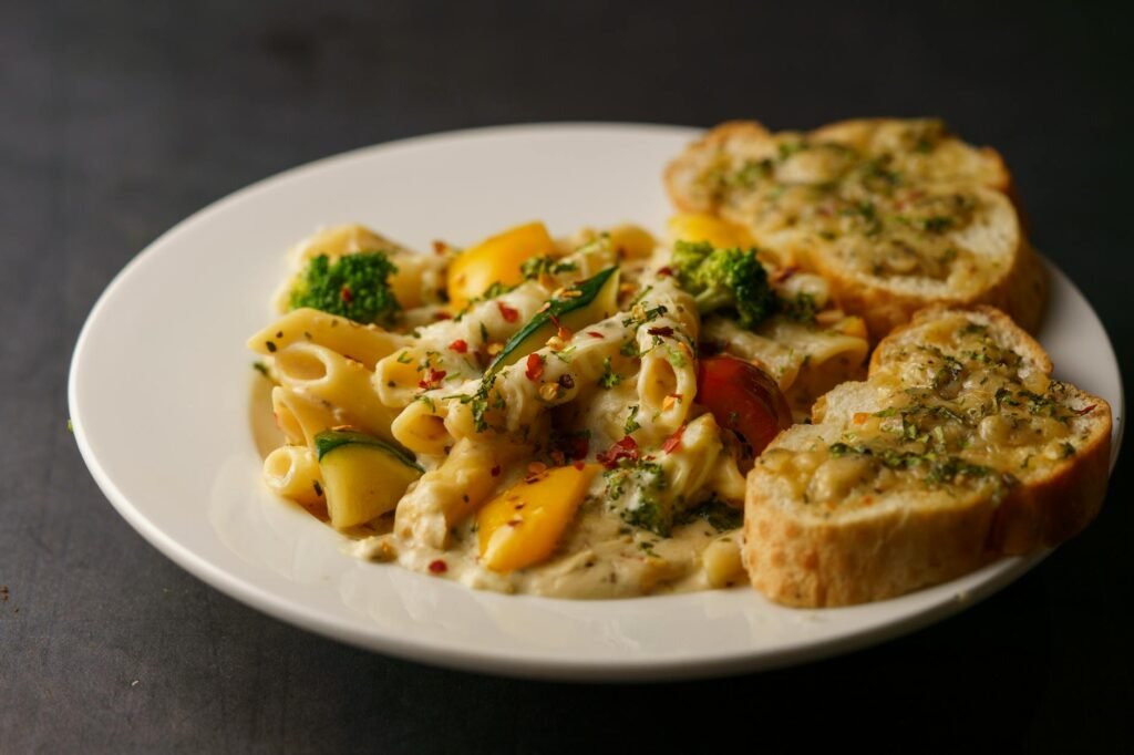 A bowl of pasta coated in creamy vegan sauce with broccoli
