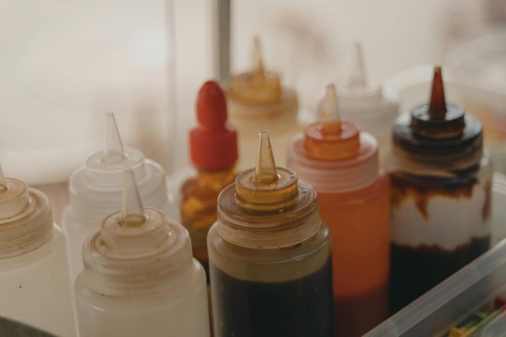 Tomato paste, soy sauce, peanut butter, vinegar, and spices arranged on a kitchen counter.