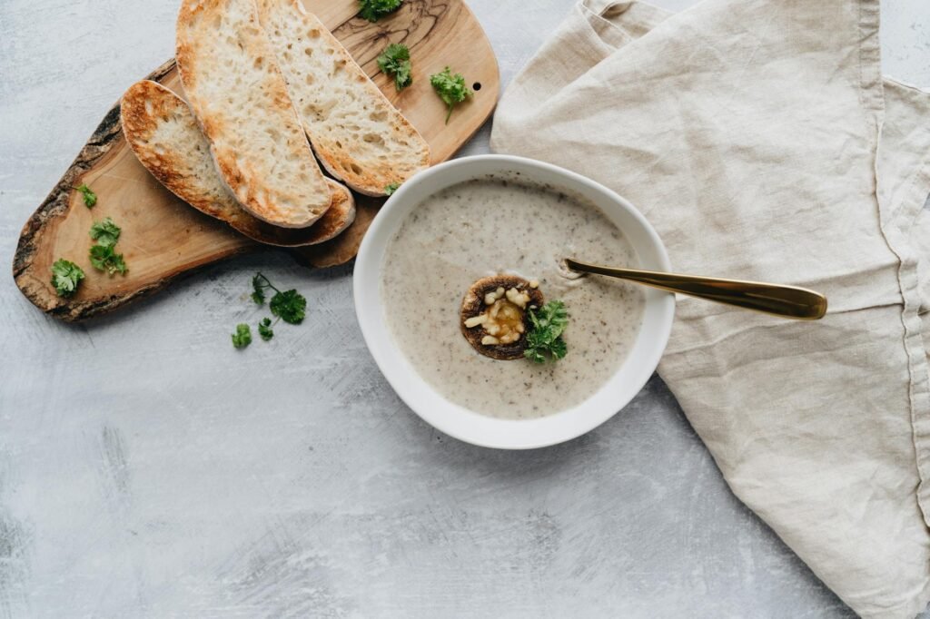 A bowl of creamy chowder topped with herbs next to slices of toasted bread.