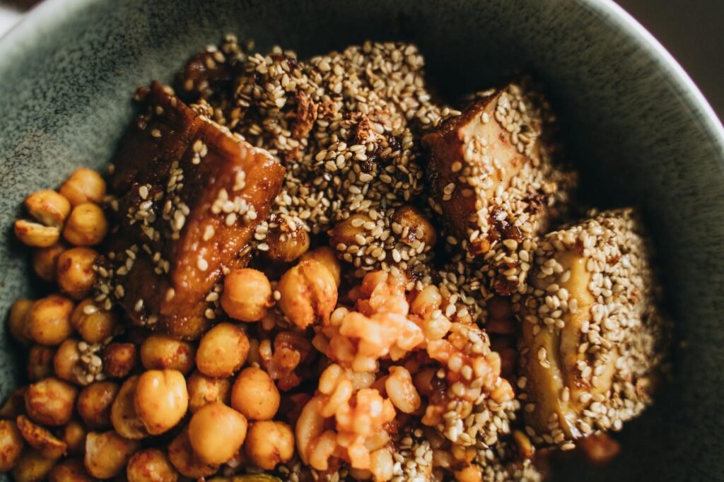 Containers filled with vegan grain bowls made from tofu, chickpeas, greens, and vegetables