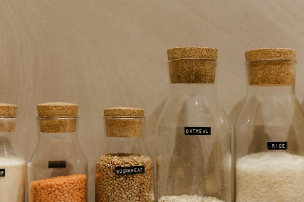 Dried beans, rice, tofu, tomato paste, vinegar, soy sauce, and spice jars arranged neatly on a counter.