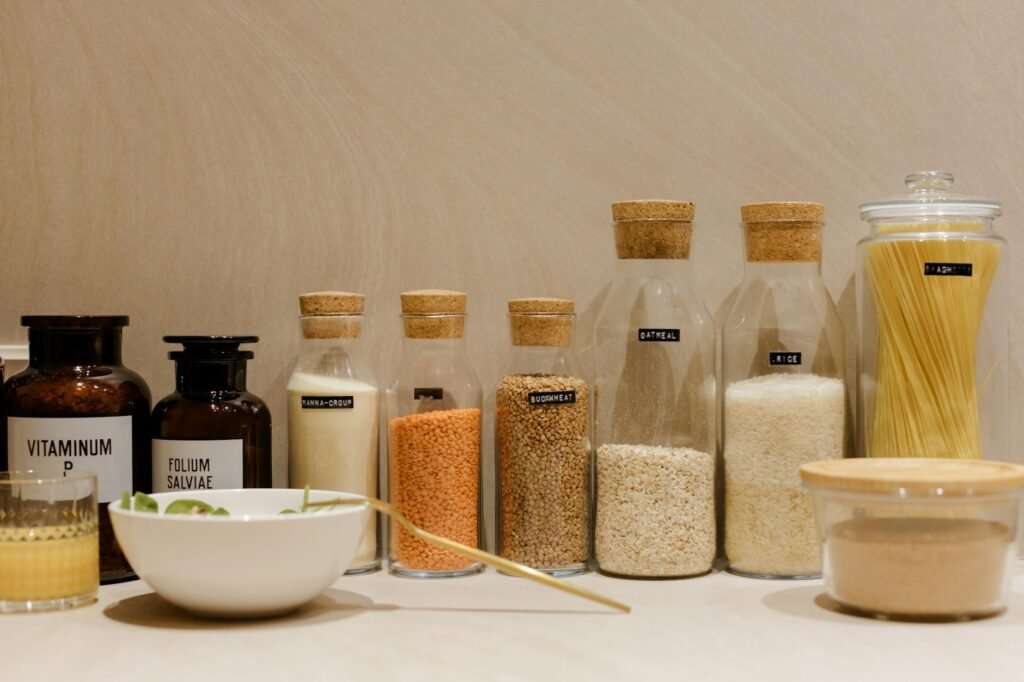 A kitchen counter with lentils, pasta, potatoes, onions, canned beans, and a handwritten meal plan.