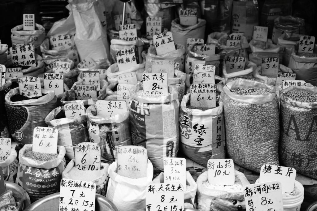 A calculator and grocery receipt beside lentils, rice, and spices on a kitchen table