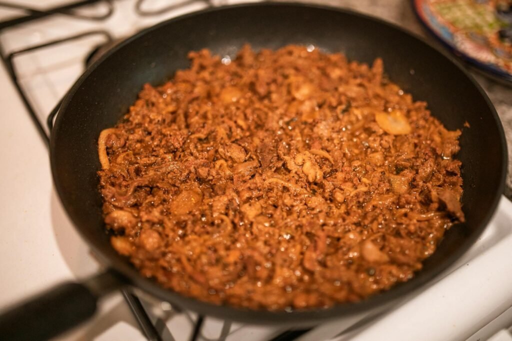 Onions and tomato paste cooking in a skillet until browned