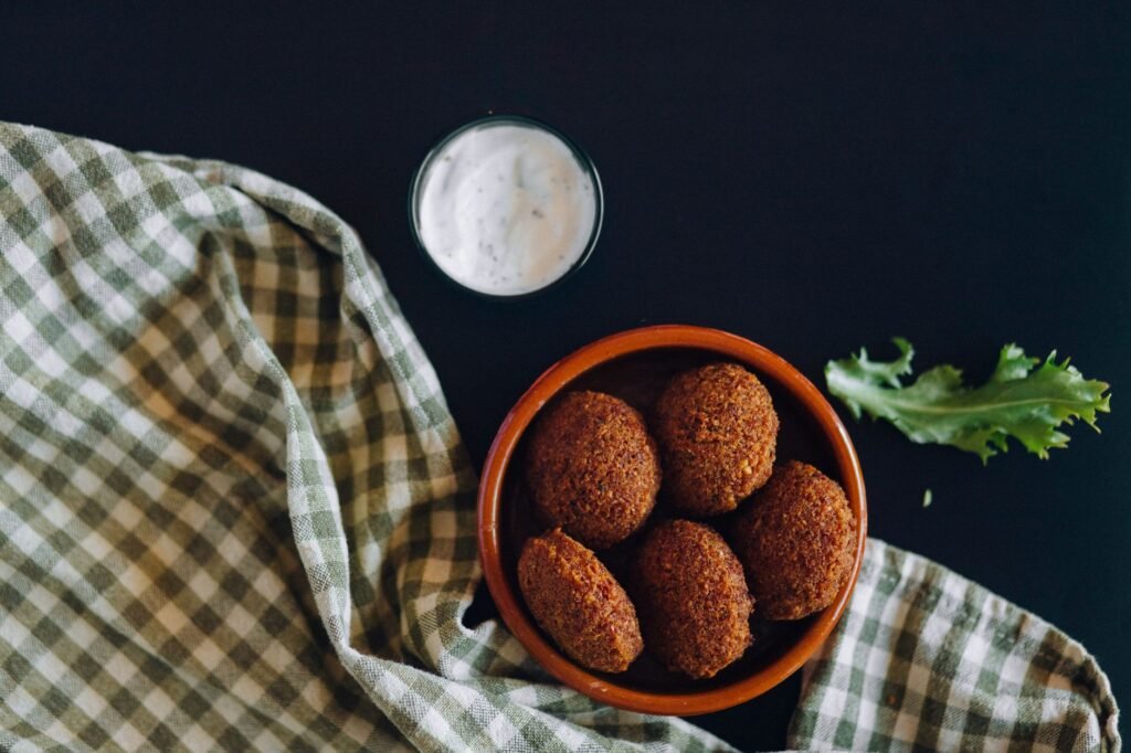Crispy chickpeas and fresh herbs being added to a bowl with a creamy sauce.