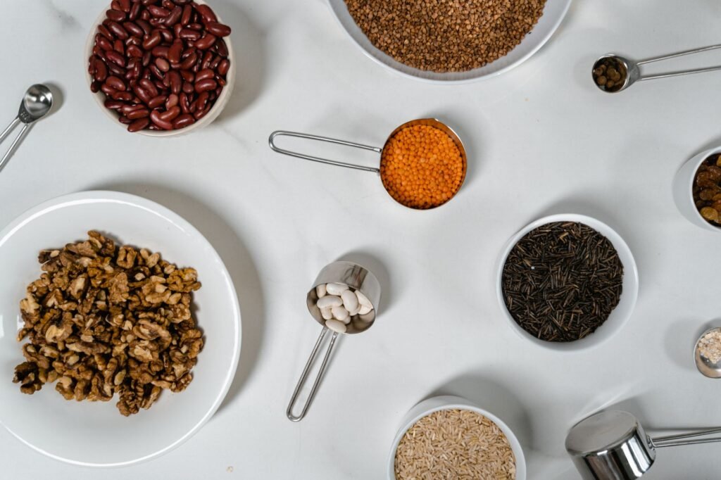 Dry beans, lentils, and chickpeas portioned in bowls on a kitchen counter with measuring cups.