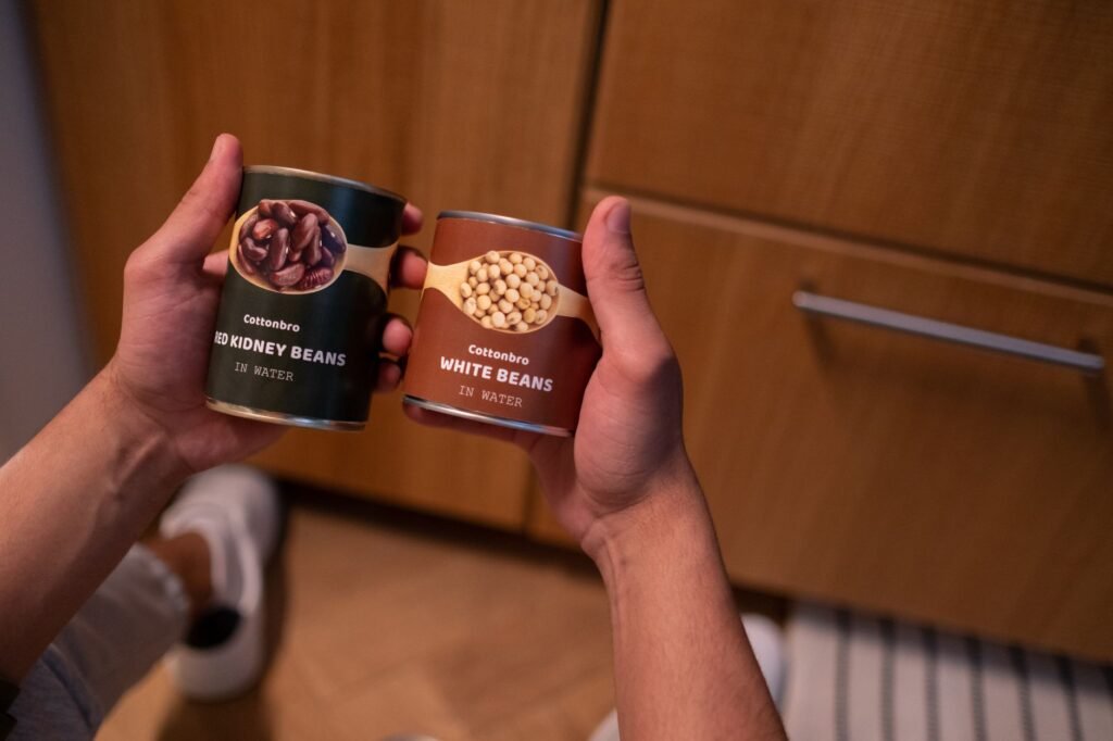 A home pantry shelf with dried beans, rice, pasta, canned tomatoes, and basic spices